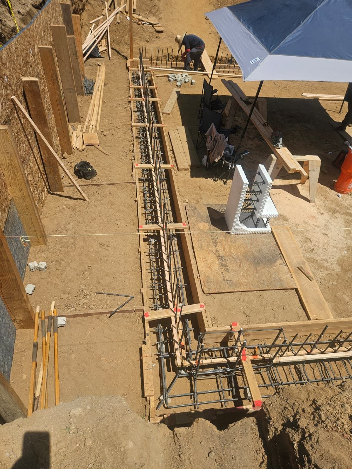 Overhead view of footing forms and rebar with a worker tying steel