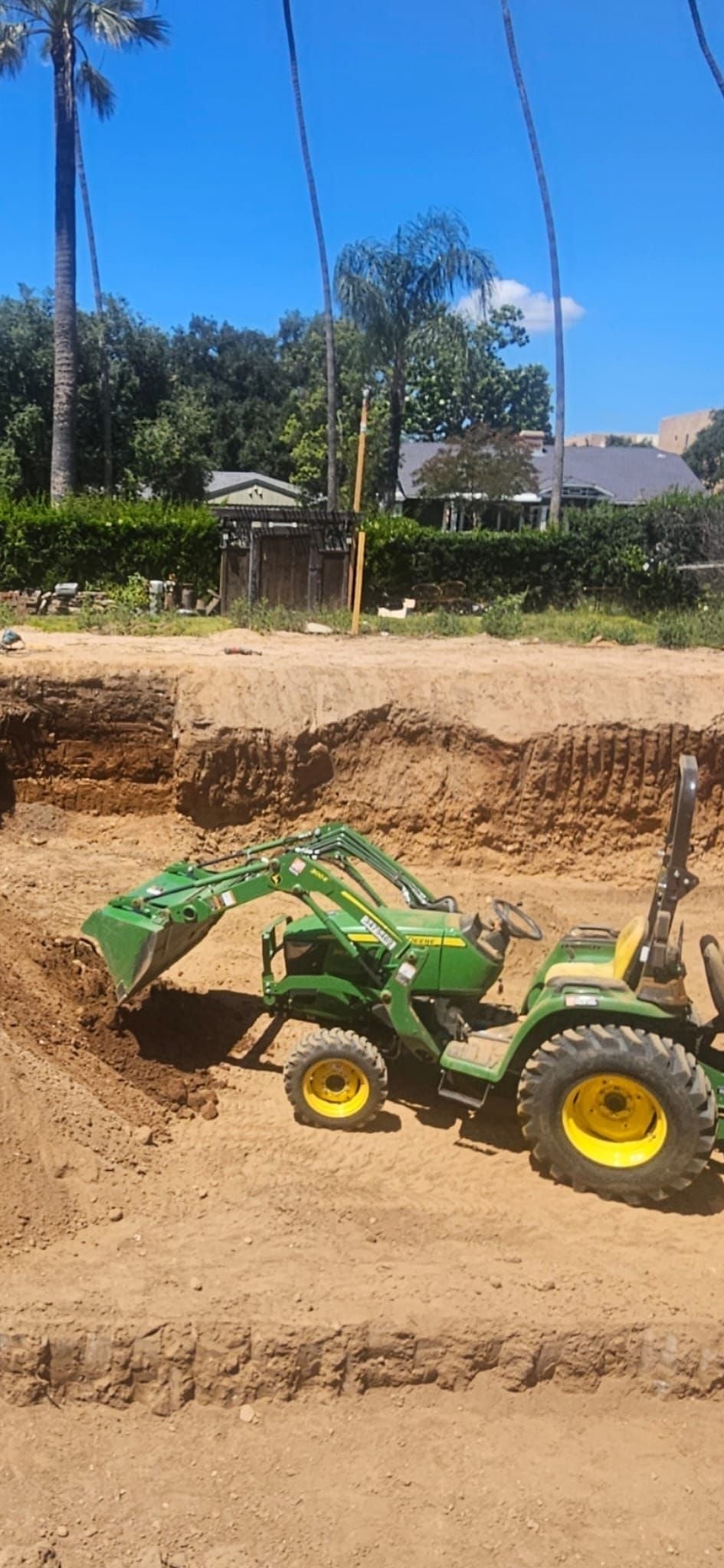 Compact tractor loader grading inside a mass excavation